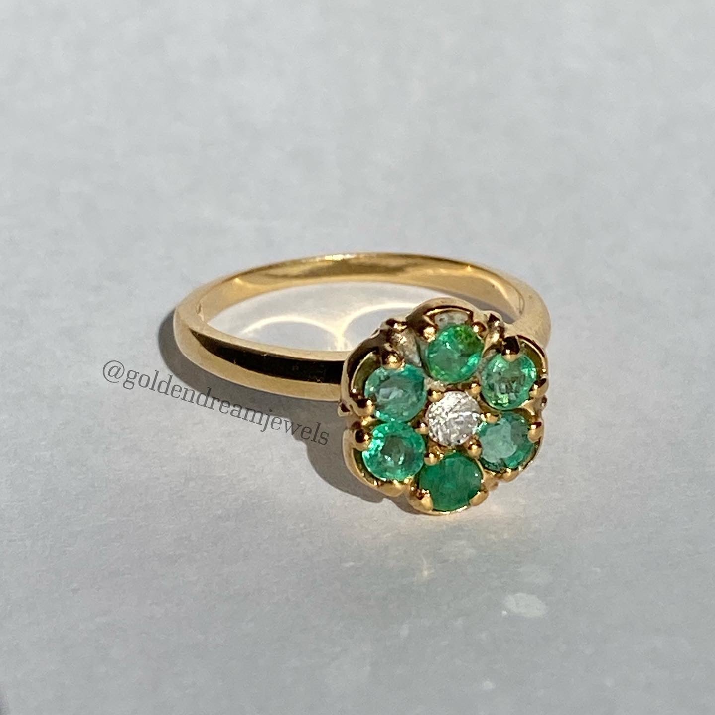 Emerald cluster ring with diamond center