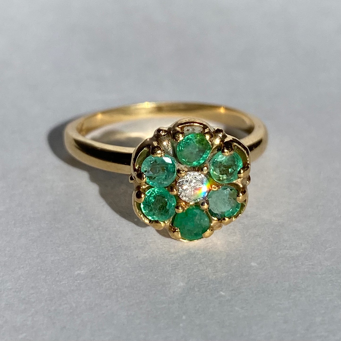 Emerald cluster ring with diamond center